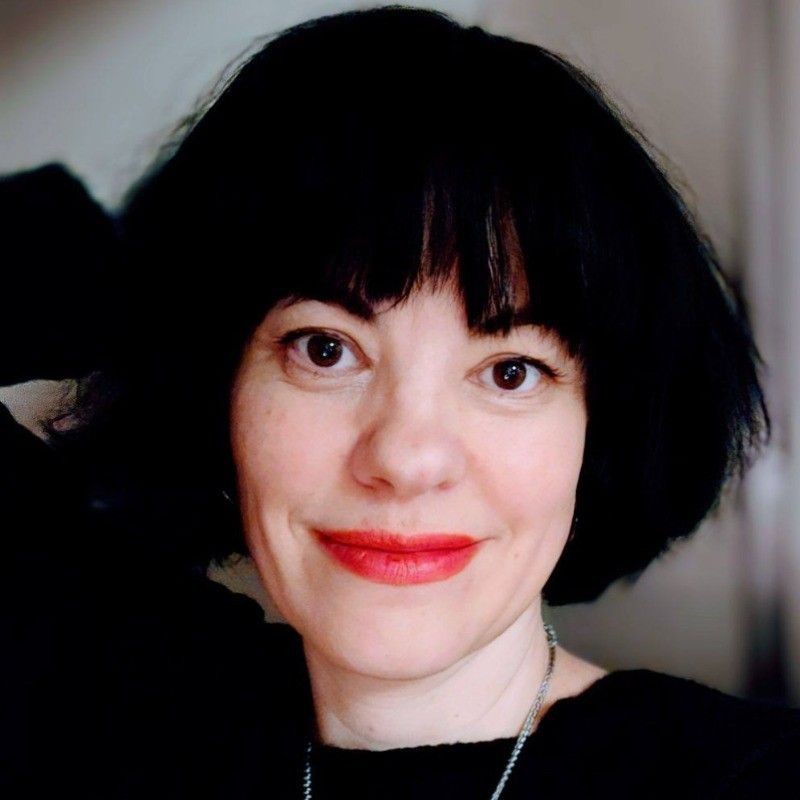 Person with short black hair and red lipstick smiling at the camera.
